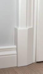 Zbliżenie na ekskluzywne białe drzwi z białą opaską, cokołem i listwą przypodłogową.