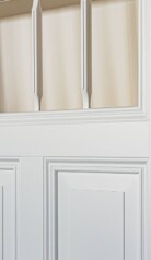 Fragment białych drzwi z frezowanymi listwami w środku.