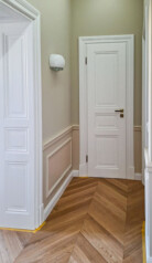 Piękne wnętrze z białymi drzwiami, ościeżnicami płycinowymi i listwami przypodłogowymi.