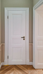 Piękne wnętrze w pastelowych kolorach z białymi drzwiami, ościeżnicami płycinowymi i listwami przypodłogowymi.