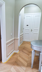 Wnętrze mieszkania z widokiem na drewniane białe drzwi wejściowe.